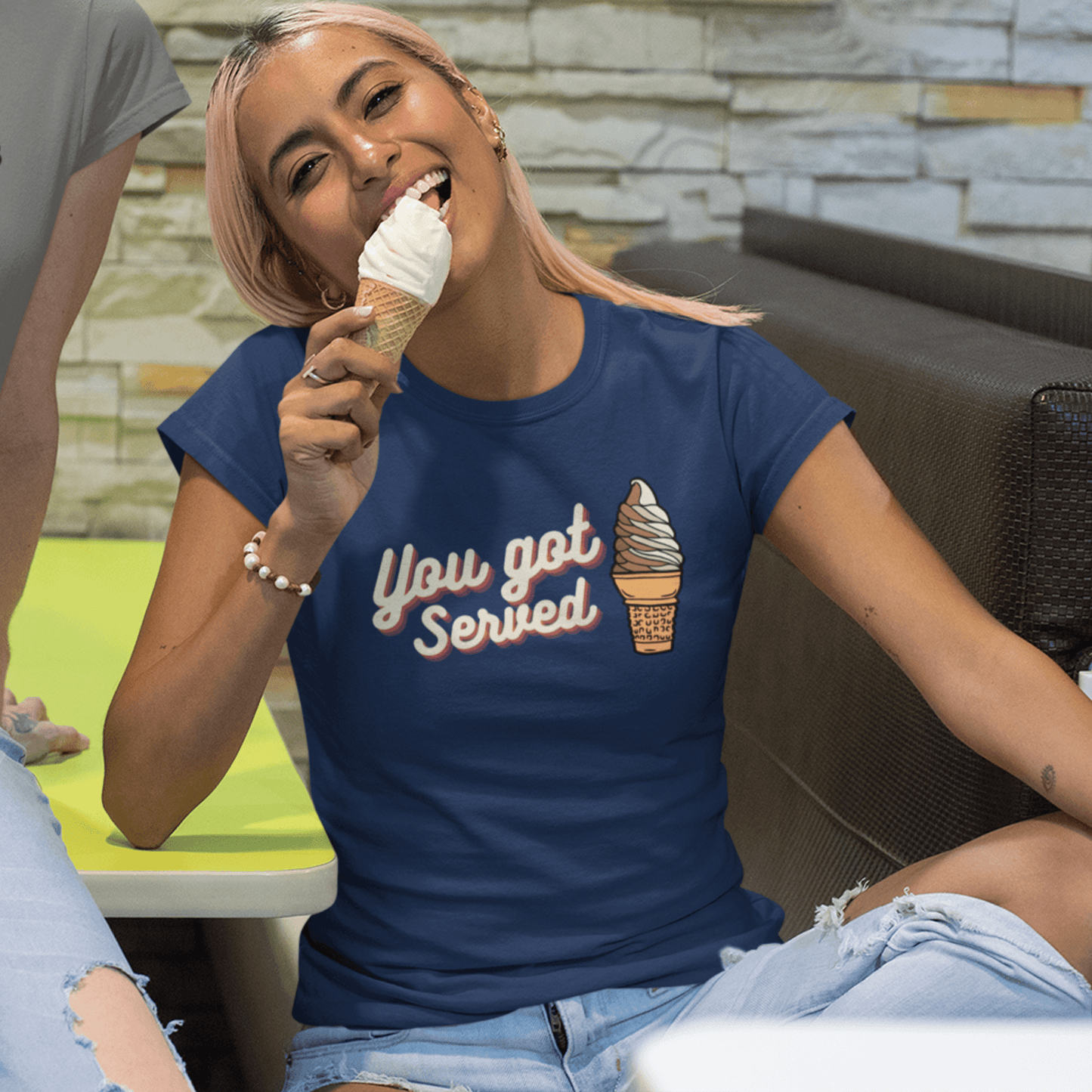 laughing woman eating soft serve ice cream cone while wearing ice cream cruise shirt